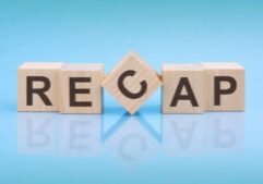 RECAP - word is written on wooden cubes close-up. blue background. white surface table